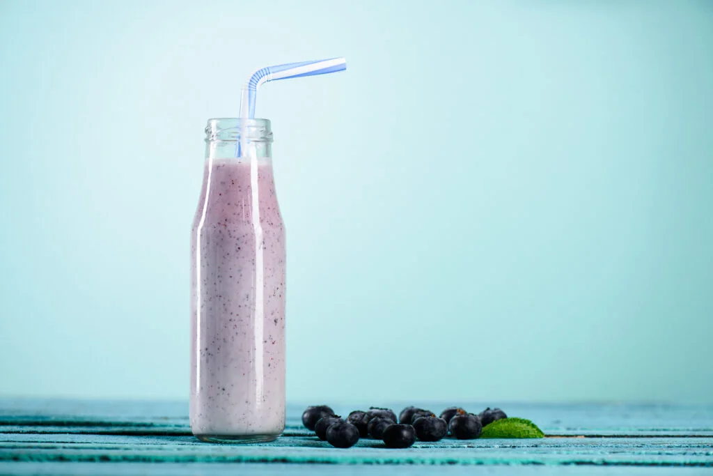 homemade blueberry milkshake in glass bottle with straw