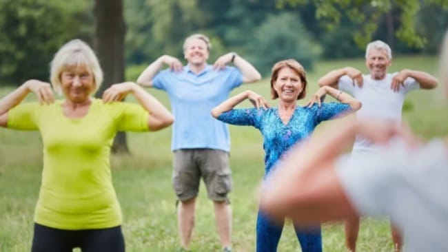Groep volwassenen doet samen een warming-up en beweegoefeningen in de buitenlucht voor een toekomstbestendige en vitale sportclub.