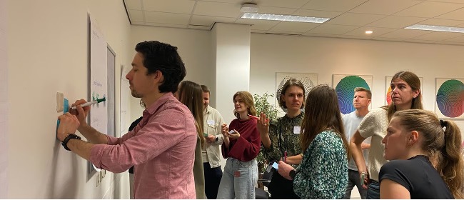 Een groep mensen in een ruimte aan het schrijven en praten.